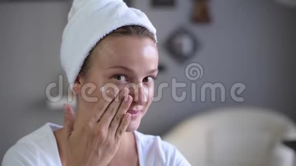 美丽的女人完美光滑的健康皮肤在她的脸上涂上保湿霜视频的预览图