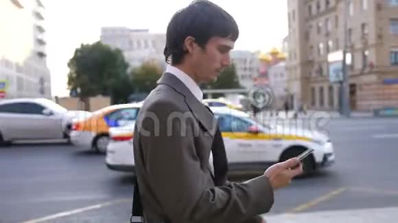 男人在户外使用触摸手机关门男人在街上用手机走路视频的预览图