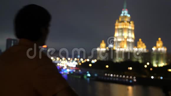 成功的年轻人站在阳台的城市天际线上莫斯科夜晚用美丽的波克看着城市的景色视频的预览图