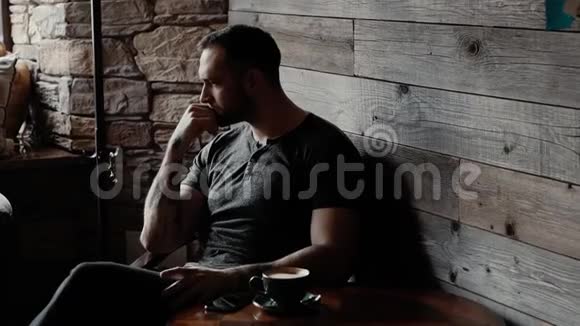 一个长着胡茬和刺青手臂的野蛮男人在咖啡店接到电话视频的预览图
