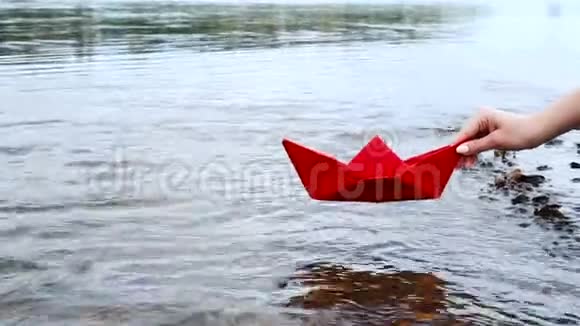 女人手把红纸船放在水面上把它推开视频的预览图