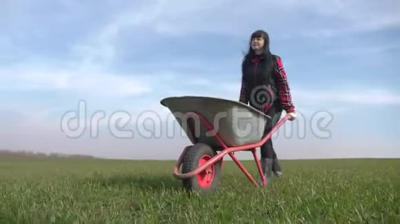 农民女孩红脖子在田里工作穿着橡胶靴的花园手推车农民生态生活方式农业视频的预览图