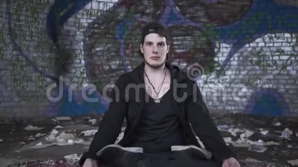 痴迷的年轻臀部坐着闭着眼睛盘腿在一个空房间与蜡烛冥想灵性视频的预览图