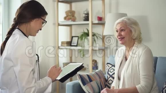 带平板电脑的医生在家中拜访了一位老年妇女视频的预览图