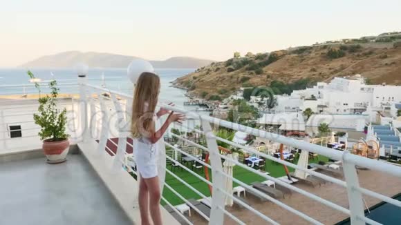 十几岁的女孩站在户外露台上有海景和山景度假村享受海上景观的旅游女孩视频的预览图