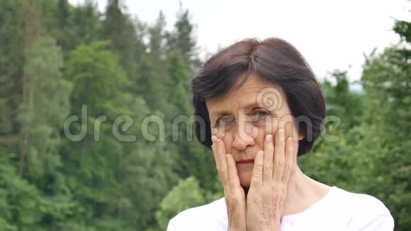 户外的一幅画上面写着一位年长的女士她留着一头乌黑的短发脸上布满皱纹带着悲伤的神情看着镜头视频的预览图