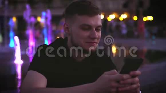 年轻英俊的千禧一代用智能手机在城市中心唐镇霓虹灯模糊的照片视频的预览图