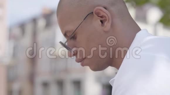 侧观英俊秃顶体贴的中东男人坐在街上户外休闲概念视频的预览图