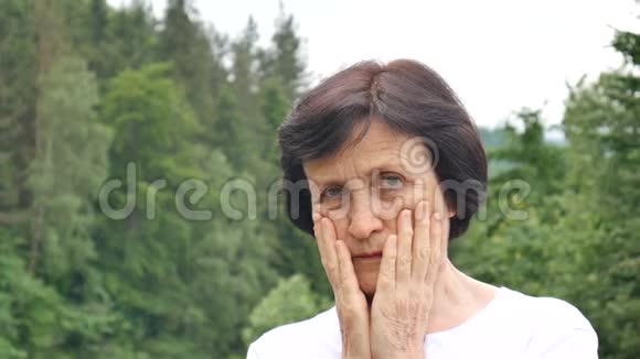 户外的一幅画上面写着一位年长的女士她留着一头乌黑的短发脸上布满皱纹带着悲伤的神情看着镜头视频的预览图