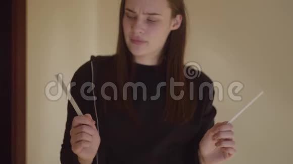 年轻悲伤紧张的女人拿着两个带有两条条纹的怀孕测试的肖像意外怀孕小女孩视频的预览图