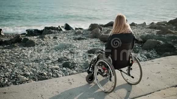 残疾妇女坐在轮椅上靠近海边看海浪视频的预览图