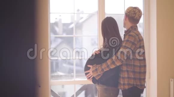 一对年轻夫妇在家那个年轻人抚摸着站在她身后的怀孕女朋友的肚子A视频的预览图