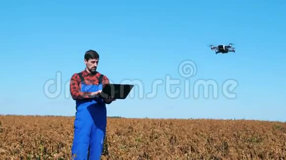 人类使用飞行无人机同时在一个有庄稼的田野上工作视频的预览图