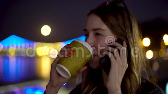 忙碌的女士通过智能手机饮料咖啡夜晚模糊的城市背景的概念画像视频的预览图