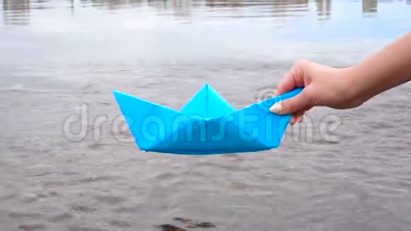女人手牵着蓝色的纸船过河视频的预览图