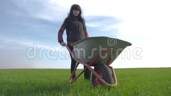 农民女孩红脖子在田里工作穿着橡胶靴的花园手推车农民生态农业耕作收获视频的预览图