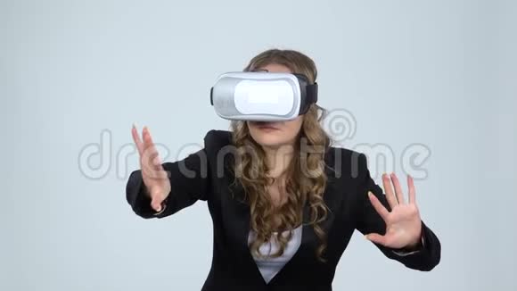 灰色背景上戴着虚拟现实眼镜的年轻女子动作缓慢视频的预览图