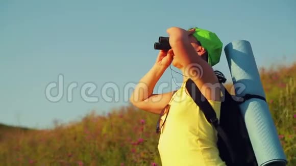女徒步旅行者在一座山上背着一个背包透过望远镜看着风景视频的预览图