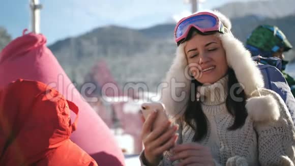 滑雪场的快乐女人坐在咖啡馆里和她的朋友在社交网络上发短信分享他的印象视频的预览图