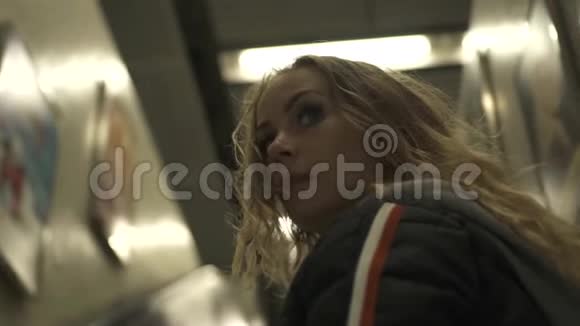 年轻女孩在m现代地铁车站地下移动楼梯在城市地铁内的自动扶梯上移动的女人办公室视频的预览图