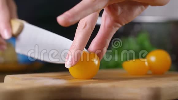 女人在厨房的木板上切黄樱桃西红柿慢动作烹饪视频的预览图