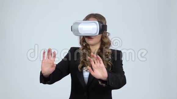 戴着虚拟现实眼镜的女人头上戴着灰色背景动作缓慢视频的预览图