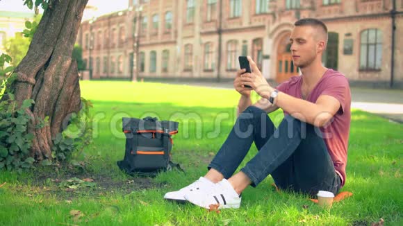 年轻人坐在树旁发短信视频的预览图