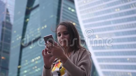 背景建筑中使用手机的漂亮女人视频的预览图