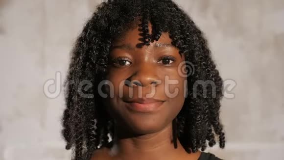 一位留着卷发的非裔美国女孩微笑着向前看视频的预览图