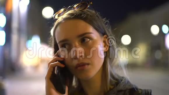 基辅市中心模糊的城市灯光下通过智能手机聊天的年轻休闲女孩的概念画像视频的预览图