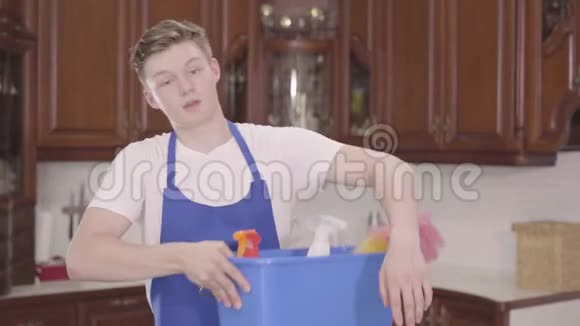 肖像年轻英俊的微笑男子拿起篮子与洗涤剂并擦拭他的额头与他的手清洁视频的预览图