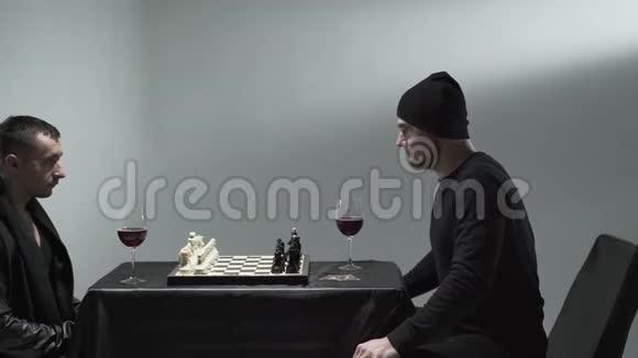 两个正在下棋的人坐在桌旁面前端着红酒杯只有一个人在行动视频的预览图