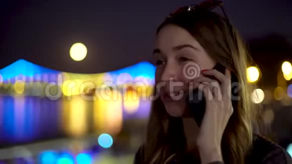 晚上一个带着咖啡和眼镜的年轻女孩在商务电话中进行情绪积极的交谈视频的预览图