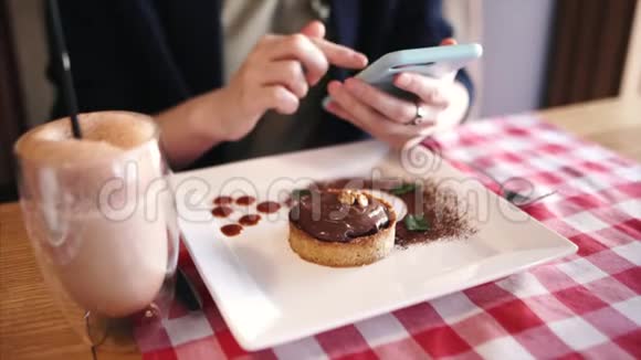 小女孩用智能手机选择食物的照片坐在咖啡馆里吃着甜点在网上翻来翻去视频的预览图