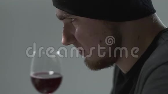 一个留胡子的家伙在酒杯里嗅酒的侧面肖像年轻人的休闲视频的预览图