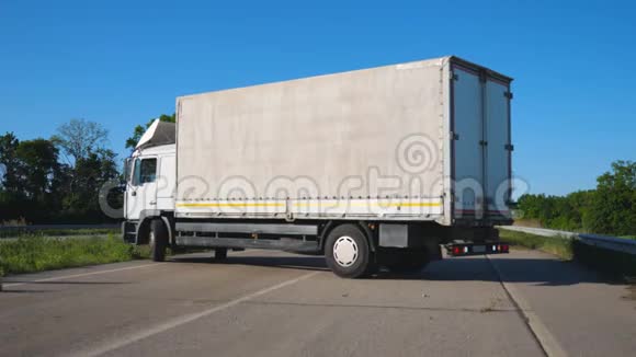 白色卡车侧面货物拖车在公路中间转弯卡车司机在车辆上运输货物视频的预览图