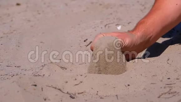 沙滩上的人手中的沙瀑布在缓慢的运动中手里拿着肮脏的沙子视频的预览图