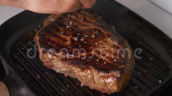 厨师把盐洒在烤牛排烧烤锅上做自制肉视频的预览图