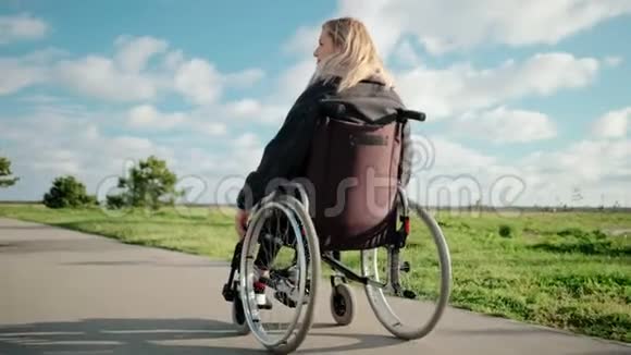 阳光明媚的一天成年残疾妇女在公园里驾驶轮椅视频的预览图