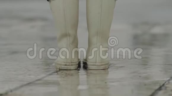好心情雨天女人穿着白色橡胶靴高脚靴在水坑里乱跑视频的预览图