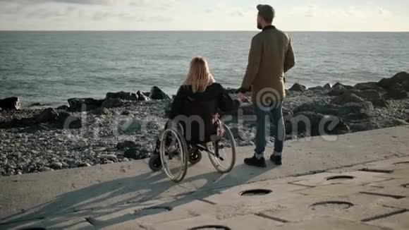女人坐在海上的轮椅上牵着丈夫的手视频的预览图