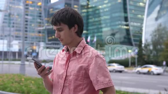 年轻英俊的商人在大工业大厦旁谈论智能手机视频的预览图