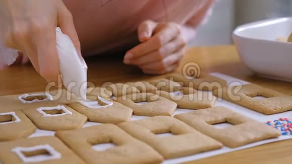 女人的手上装饰着糖甜的姜饼屋用的冰曲奇烹饪自制姜饼屋视频的预览图