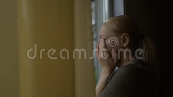 女人站在房间的窗户边哭着用手捂住脸外面雨滴在地上视频的预览图