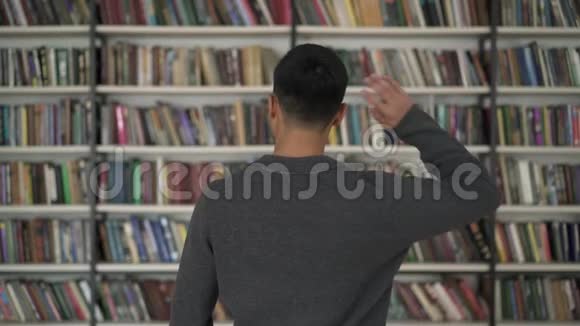 在书架上选书的有色人种挠头视频的预览图