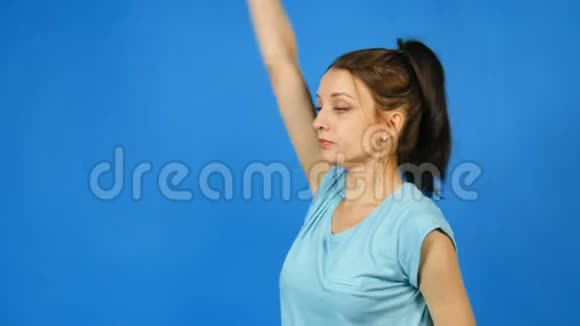 漂亮的年轻运动女性手中有哑铃在蓝工作室背景下做运动一个漂亮的女孩视频的预览图