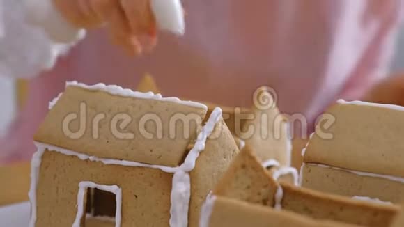 女人手使姜饼屋的细节与糖甜糖霜烹饪自制姜饼屋视频的预览图