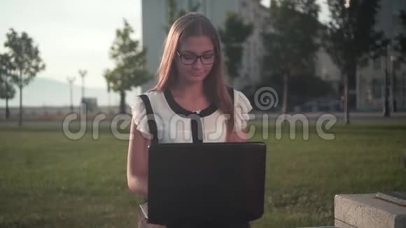 穿白衬衫戴眼镜的女商人坐在长凳上在笔记本电脑上工作那女孩对这项工作感到惊讶视频的预览图