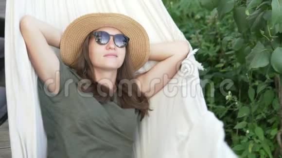 戴帽子的女人夏天在小屋的吊床上摇摆视频的预览图