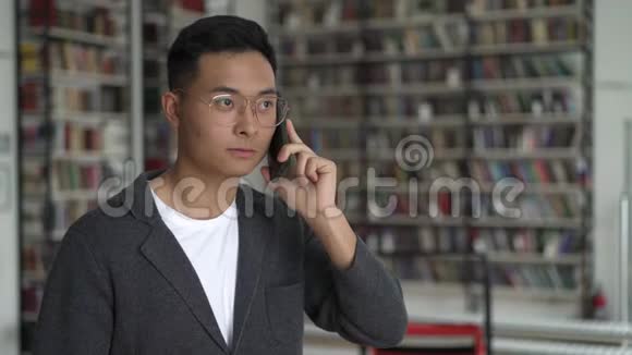 亚洲年轻人在书架背景下打电话视频的预览图